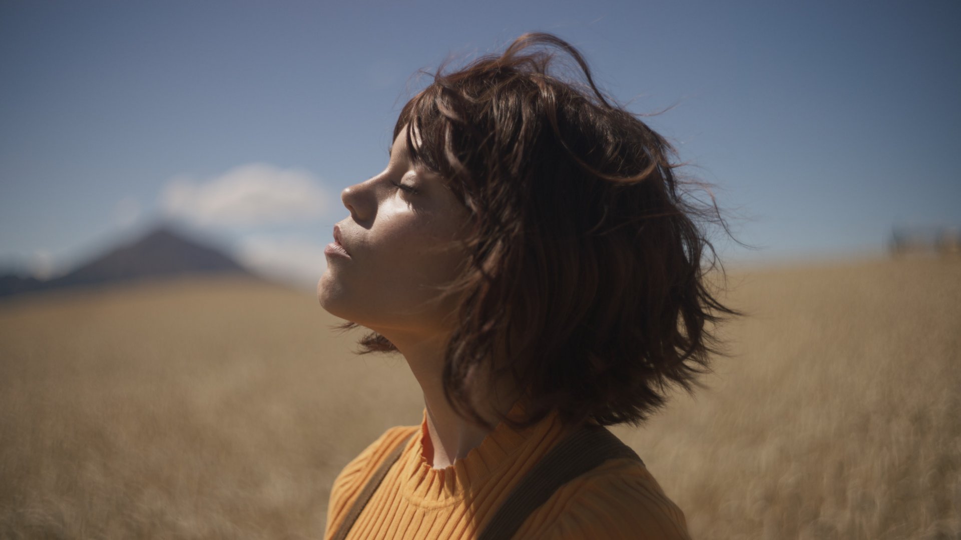 Jenna Ortega as Klara looking toward sunlight in a field in Klara and the Sun