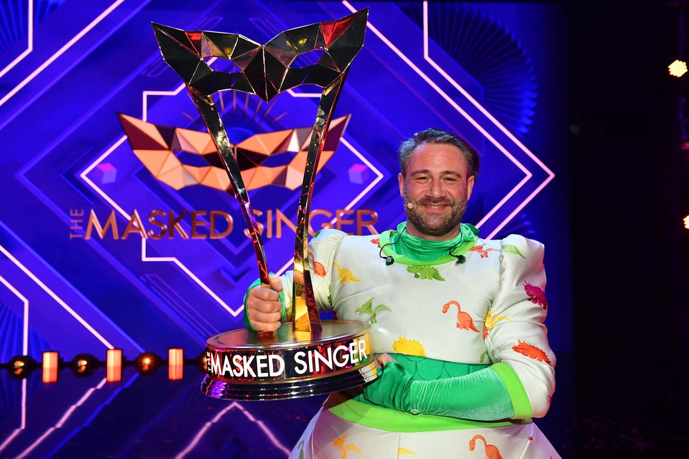 Masked Singer Staffel 4 Sieger: Der Dino bzw Sänger Sasha mit der Trophäe
